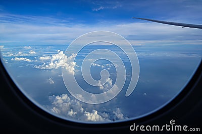 Flying on the plane seeing sunrise light on abstract white cloud and shades of blue sky background with airplane wing Stock Photo