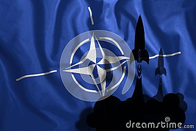 The flying rockets fluttered against the background of the NATO flag in the wind. Symbol, war, conflict Stock Photo