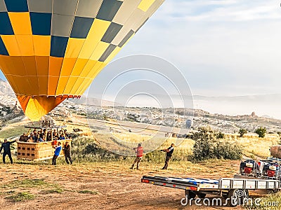 Flying in sky many bright colored beautiful balloons into air in Cappadocia in mountains early at sunrise, dawn. Filling Editorial Stock Photo