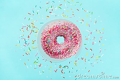 Flying sprinkled pink donut. Sweet doughnut on pastel blue background Stock Photo