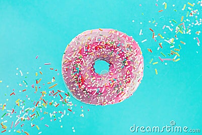 Flying sprinkled pink donut. Sweet doughnut on pastel turquoise background Stock Photo