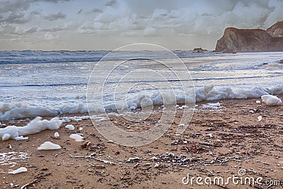 Foam on a polluted beach Stock Photo