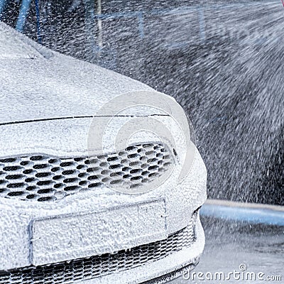 Foam is pouring onto the car under pressure. car wash Stock Photo