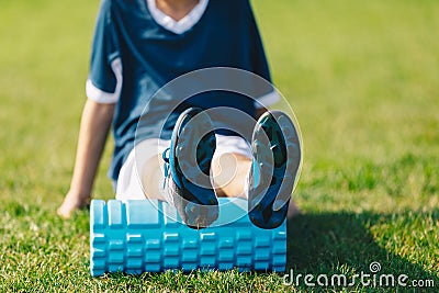 Foam Rolling. Young Soccer Player in Soccer Cleats Using Training Foam Roller Stock Photo