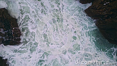 Foamy ocean water bubbling between coastal rocks. Aerial stormy sea splashing Stock Photo