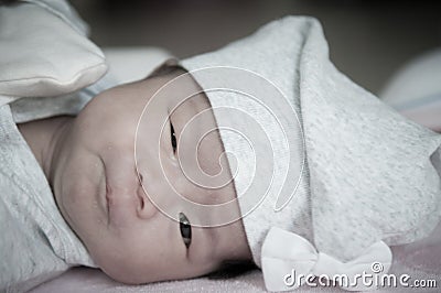 Focus at Asian baby girl with gray hat while sleeping and playing on the bed / Close up at cute newborn is looking at camera Stock Photo