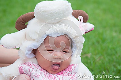 Focus at Asian newborn baby girl with costumes little sheep in the garden and mother is holding her. Stock Photo