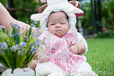 Focus at Asian newborn baby girl with costumes little sheep in the garden and mother is holding her. Stock Photo