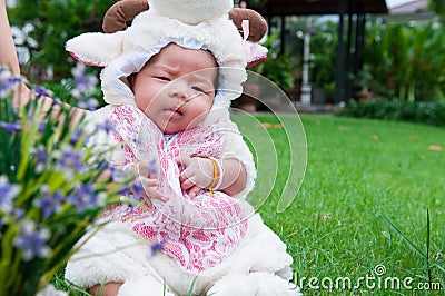 Focus at Asian newborn baby girl with costumes little sheep in the garden and mother is holding her. Stock Photo