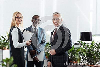 Focus of cheerful businessmen and businesswoman standing in office Stock Photo