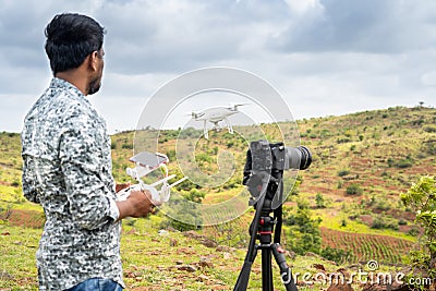 Focus on drone, Young videographer filming video by controlling drone using remote controller - concept of professional drone Stock Photo