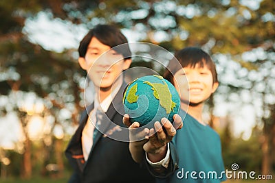 Focus Earth with blurred asian boy and businessman holding globe together. Gyre Stock Photo