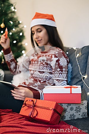 In focus gift boxes and blurred woman holding tablet and card Stock Photo