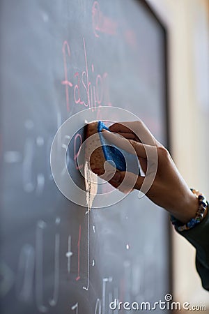 Focus on hand of young student or teacher wiping blackboard with wet sponge Stock Photo