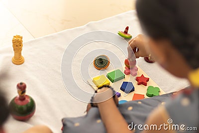 Focus on hands of cute little child girl playing with Indian wooden channapatna toys in the room Stock Photo