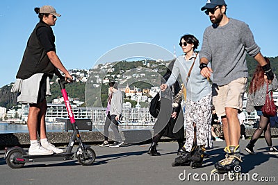 Focus on people walking with closer people skating and scooting along Great harbour Walk on city`s water edge Editorial Stock Photo