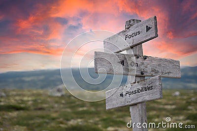 focus on possibilities text engraved in wooden signpost outdoors in nature during sunset Stock Photo