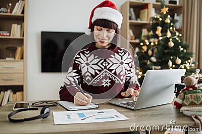 Focus on woman hand with pen in Santa hat making notes on draft paper document Stock Photo