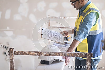 Focused architect holding clipboard with apartment drawing blueprint in hand Stock Photo