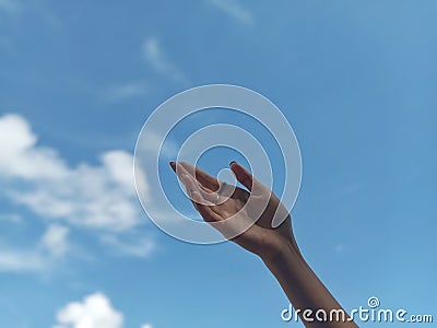 Focused and Artistic Hand with Blurred Blue Sky Background Stock Photo