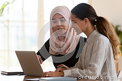 Asian muslim female mentor teaching caucasian intern explaining computer work Stock Photo