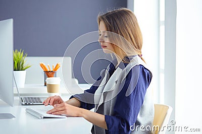 Focused attentive woman in headphones sits at desk with laptop, looks at screen, makes notes, learns foreign language in Stock Photo