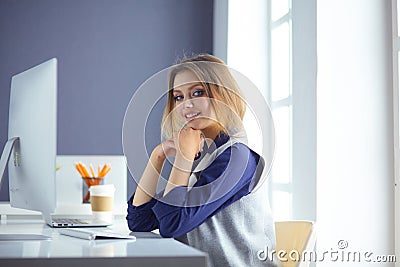 Focused attentive woman in headphones sits at desk with laptop, looks at screen, makes notes, learns foreign language in Stock Photo