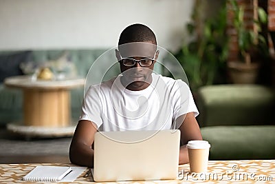 Focused black man studying on laptop drinking coffee Stock Photo
