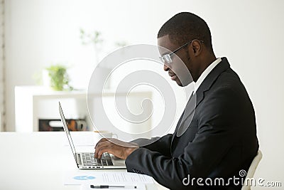 Focused black worker working at laptop at company workplace Stock Photo