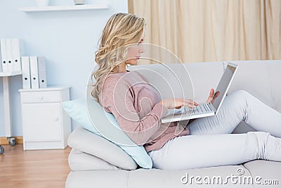Focused blonde on couch using laptop Stock Photo