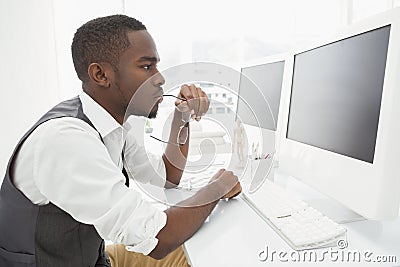 Focused businessman holding glasses and using computer Stock Photo