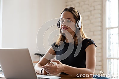 Focused businesswoman wearing headset looking at laptop screen and talking Stock Photo