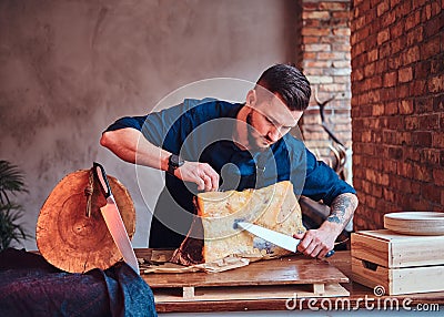 Focused chef cook cutting exclusive jerky meat on a table in kitchen with loft interior. Stock Photo