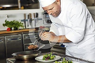 Focused chef prepares steak dish at gourmet restaurant Stock Photo