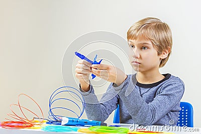 Focused child with 3d printing pen creating a plane Stock Photo