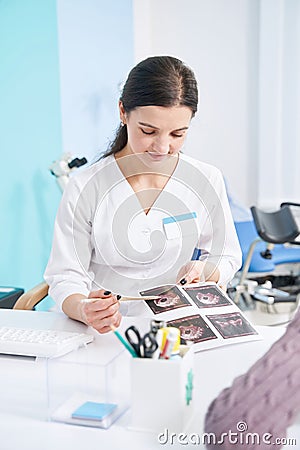 Focused diagnostician looking at ultrasound pictures in her hands Stock Photo