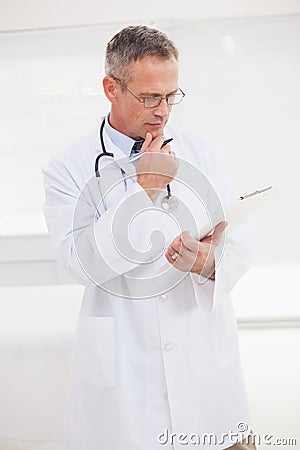 Focused doctor looking over medical notes Stock Photo