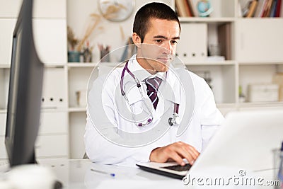 Focused doctor working with laptop in office Stock Photo