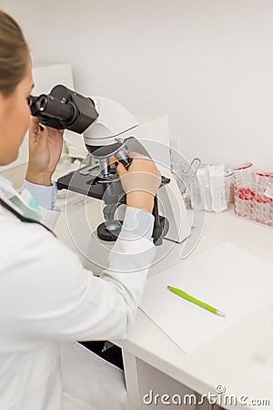 Focused female science student looking in a microscope in a laboratory Stock Photo