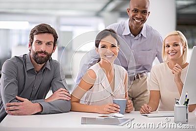 Focused on the future. a group of smiling businesspeople gathered at their desk. Stock Photo