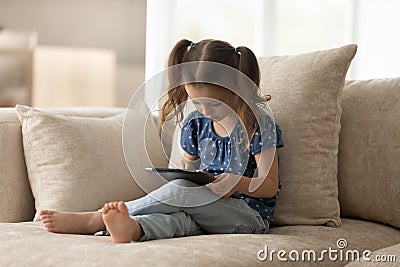 Focused gen Z preschooler kid using tablet at home Stock Photo