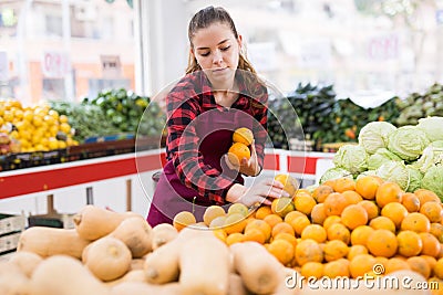 Focused girl salesperson in a store puts the tangerines on the counter Stock Photo