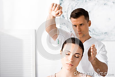 Hypnotist standing near woman with closed eyes and holding green stone Stock Photo