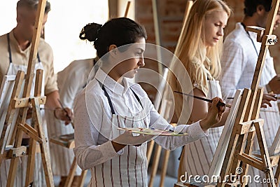 Focused inspired Indian artistic class student girl drawing in paints Stock Photo
