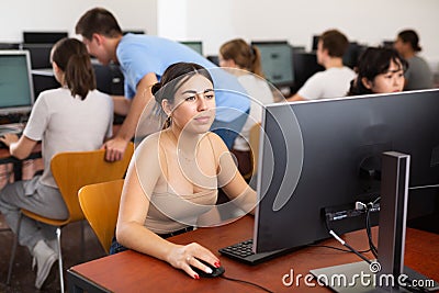Focused Latin female teenager solving tasks of computer science in the auditory Stock Photo