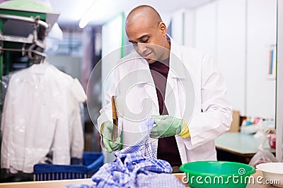 Focused man drycleaner removing spots and stains Stock Photo