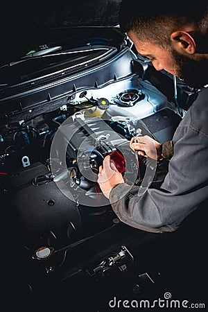 Focused mechanic doing car repair. Disconnecting the battery terminal of modern car. Stock Photo
