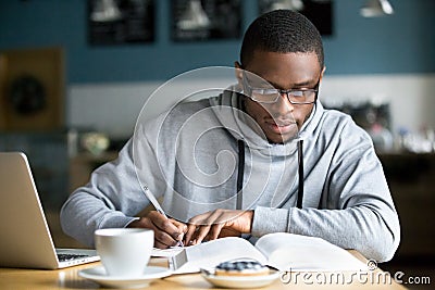 Focused millennial african student making notes while studying i Stock Photo