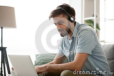 Focused millennial man in headset using computer online Stock Photo
