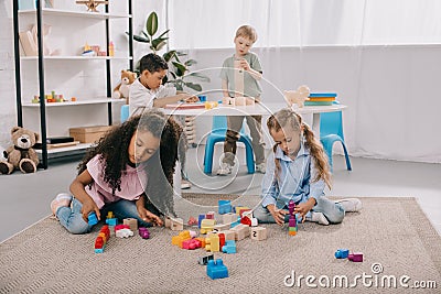 focused multiracial preschoolers playing with wooden blocks Stock Photo